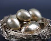 Four eggs painted gold, sitting in a golden nest to represent a retirement "nest egg"