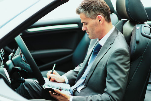Businessman writing notes in his car
