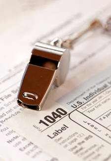 Silver whistle sitting on a 1040 form to signify reporting tax fraud