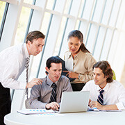 Group of employees huddled around a laptop, looking at the screen