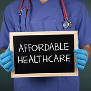 Nurse holding a chalkboard sign with the phrase "Affordable Healthcare" written on it