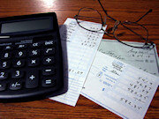 Calculator, a few checks, and a pair of glasses sitting on a desk