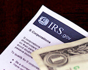 S Corporation form with a one dollar bill sitting on top of it 