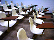 Rows of empty chairs with desks in a school auditorium setting