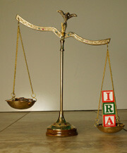 Brass scales with letter blocks spelling IRA weighing down one side
