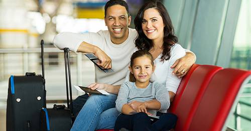Family of three sitting in an airport and smiling